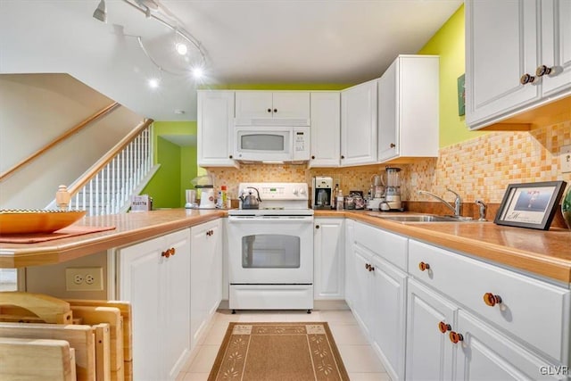 kitchen featuring white appliances, a sink, white cabinetry, and decorative backsplash