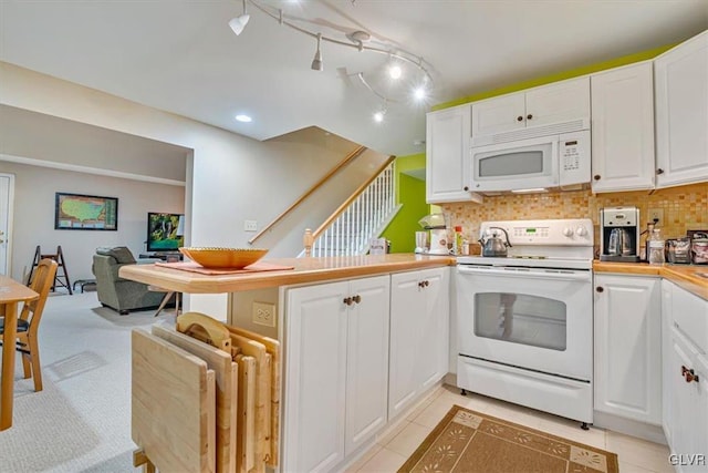 kitchen featuring white appliances, decorative backsplash, a peninsula, light countertops, and white cabinetry