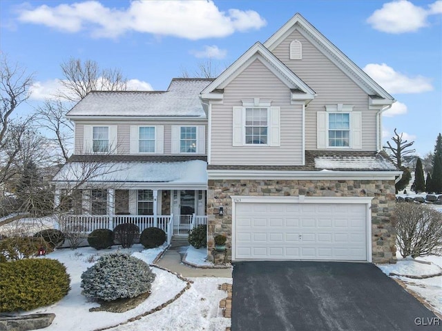 view of front of house with aphalt driveway, covered porch, stone siding, and a garage