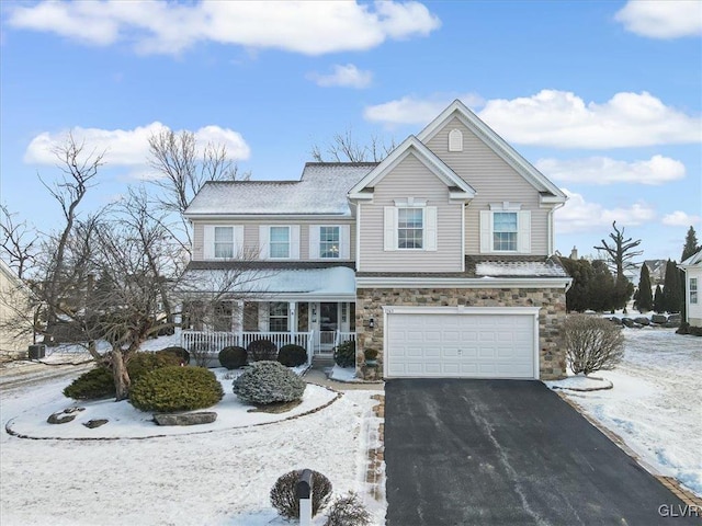 traditional-style home with stone siding, a porch, an attached garage, and aphalt driveway