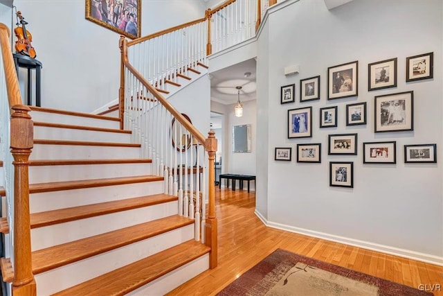 stairs with a towering ceiling, baseboards, and wood finished floors