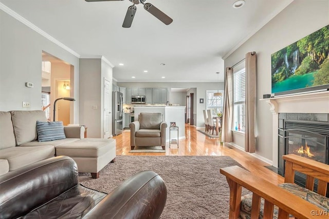 living room with ornamental molding, a tile fireplace, light wood finished floors, and recessed lighting