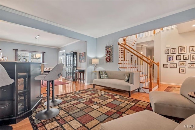 living area featuring baseboards, crown molding, stairway, and wood finished floors