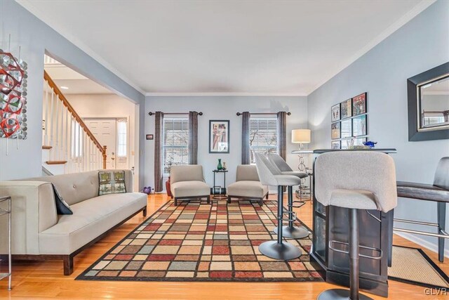 living area with ornamental molding, stairway, and wood finished floors