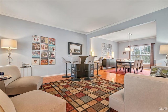 living room featuring ornamental molding, a dry bar, wood finished floors, and baseboards