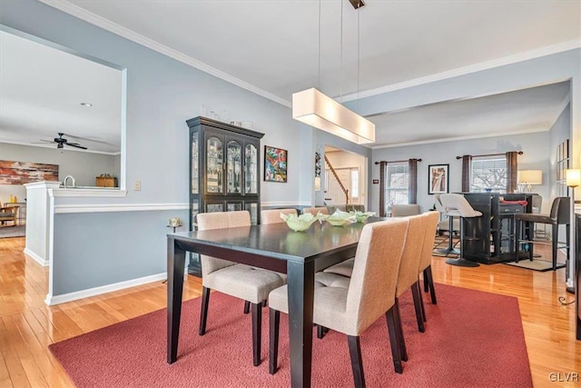 dining area featuring a ceiling fan, light wood-type flooring, crown molding, and baseboards