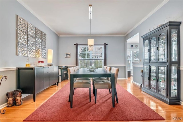 dining room featuring light wood-style floors, baseboards, and ornamental molding