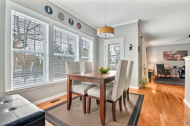 dining area with visible vents, ornamental molding, light wood-style flooring, and baseboards