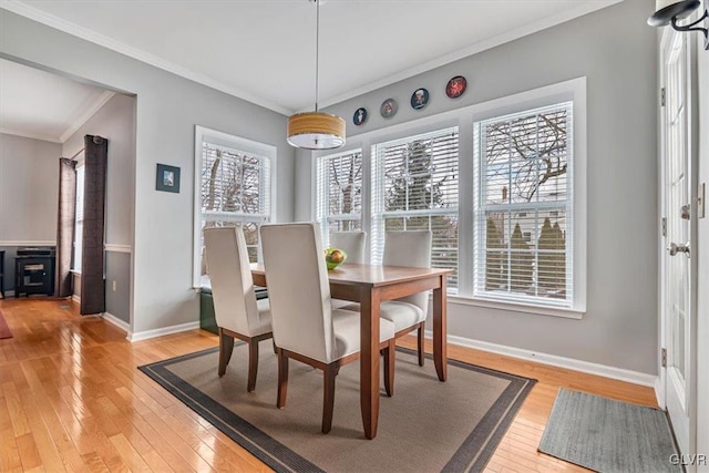 dining space featuring crown molding, light wood-style flooring, and baseboards