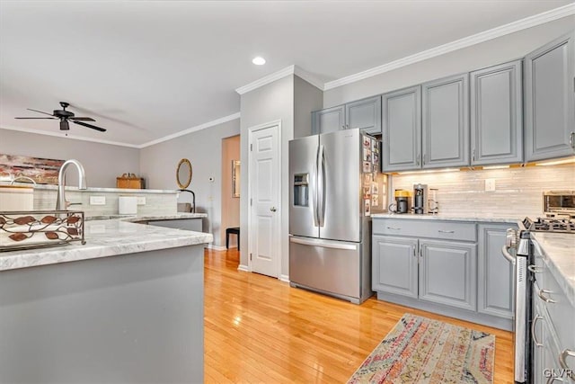 kitchen with a sink, appliances with stainless steel finishes, gray cabinets, and decorative backsplash