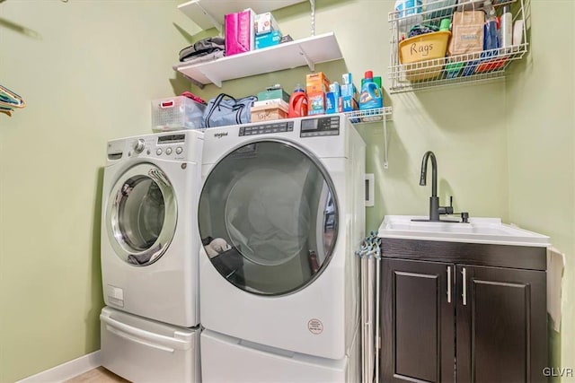 laundry room with a sink, washing machine and clothes dryer, cabinet space, and baseboards