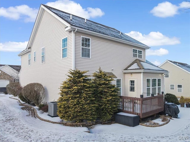 snow covered property with a deck and central AC