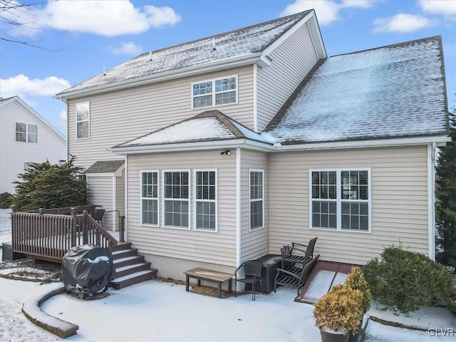 snow covered rear of property featuring roof with shingles and a wooden deck