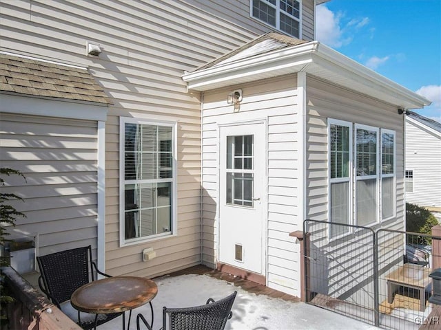 property entrance featuring a patio and a shingled roof