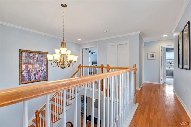 hallway with baseboards, ornamental molding, an upstairs landing, light wood-type flooring, and a chandelier