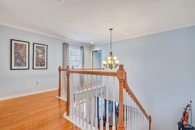 corridor featuring a notable chandelier, an upstairs landing, baseboards, light wood-style floors, and crown molding