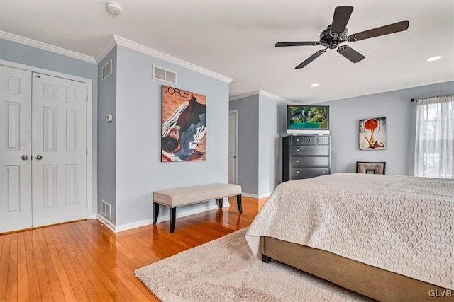 bedroom featuring light wood-type flooring, visible vents, crown molding, and baseboards