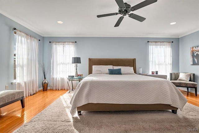 bedroom featuring ceiling fan, multiple windows, wood finished floors, and crown molding