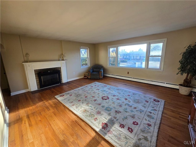 unfurnished living room with baseboards, a fireplace with flush hearth, baseboard heating, and wood finished floors