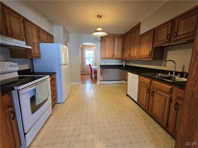 kitchen featuring under cabinet range hood, a sink, dark countertops, white appliances, and light floors