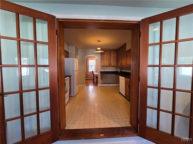 hall featuring arched walkways, baseboard heating, and light floors