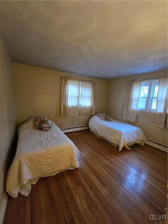 bedroom with a baseboard radiator and wood finished floors