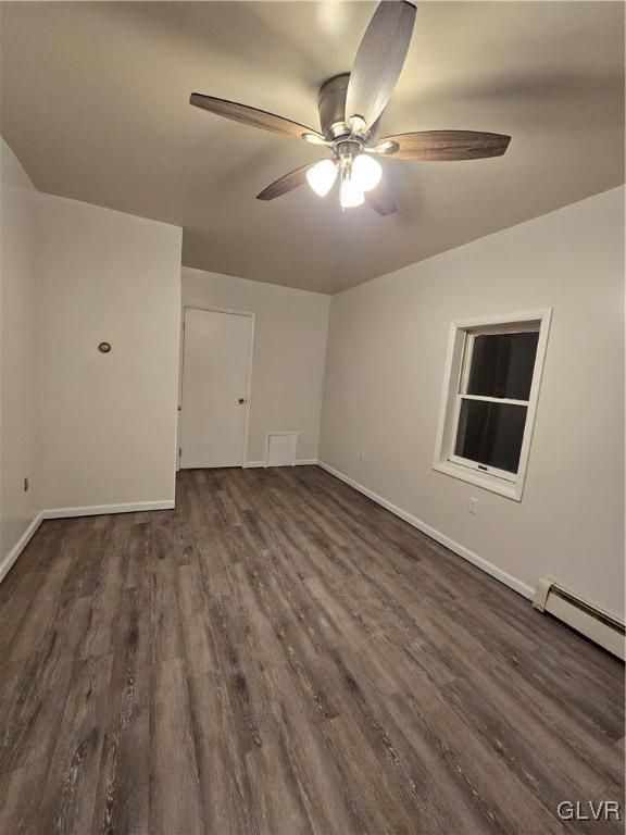 unfurnished room with a ceiling fan, baseboards, baseboard heating, and dark wood-style flooring