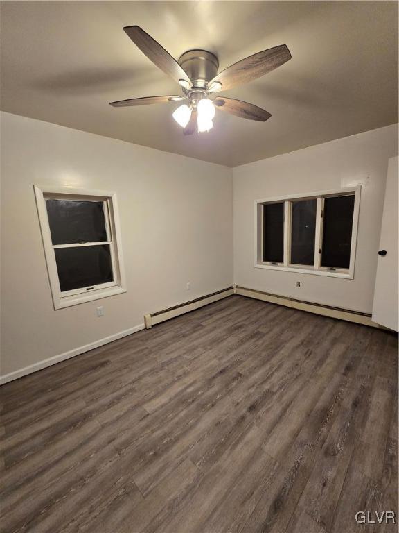 spare room featuring baseboards, a baseboard heating unit, dark wood-type flooring, and a ceiling fan