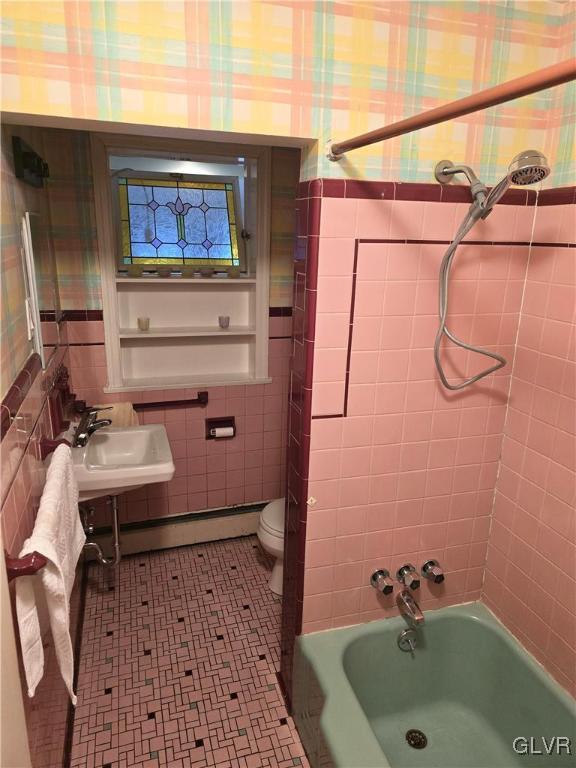 bathroom featuring a baseboard radiator, wallpapered walls, a sink, tile walls, and toilet