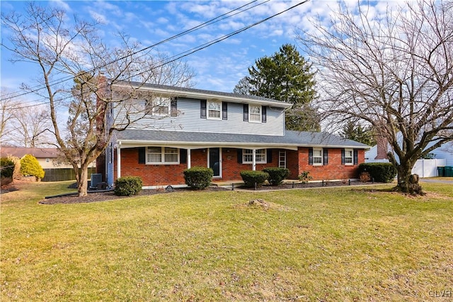 view of front of house featuring brick siding, fence, a front lawn, and central AC unit