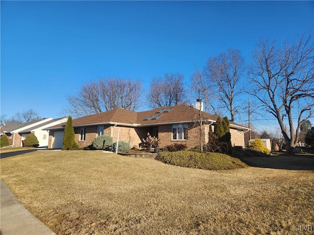 view of property exterior with brick siding, a lawn, a chimney, a garage, and driveway