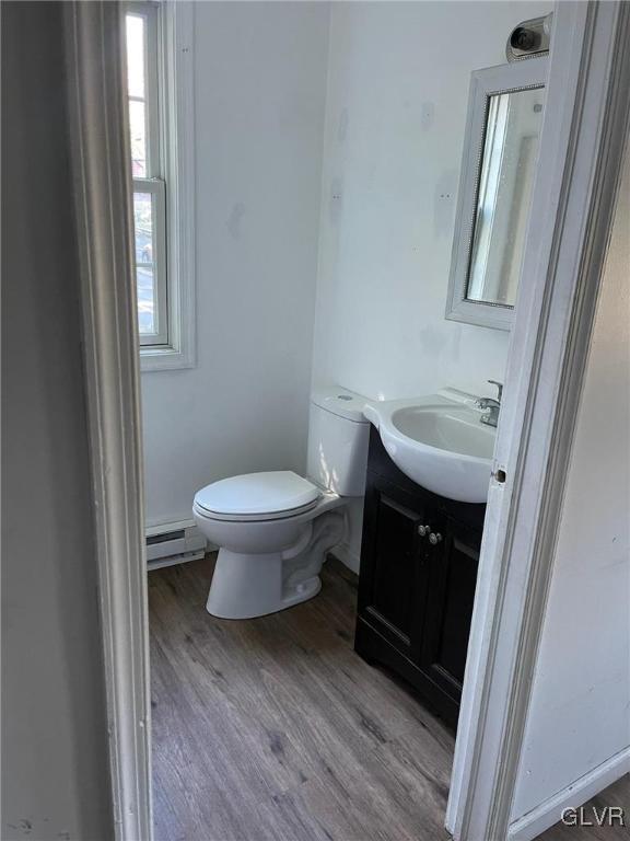 bathroom with baseboard heating, wood finished floors, vanity, and toilet