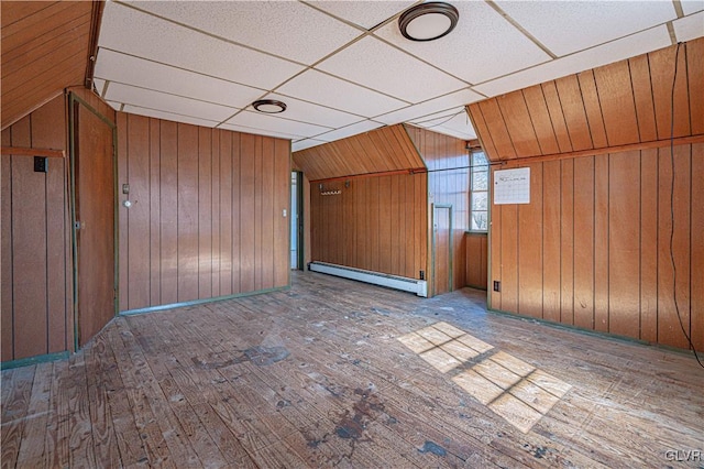 empty room with wood walls, hardwood / wood-style flooring, and a baseboard radiator