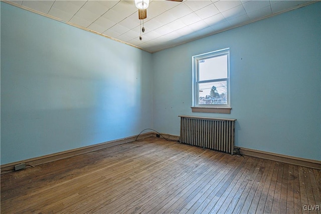 empty room featuring crown molding, radiator heating unit, ceiling fan, and wood-type flooring