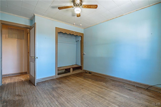 unfurnished bedroom with a ceiling fan, visible vents, a closet, wood-type flooring, and crown molding