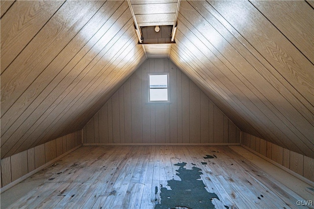 additional living space featuring wood-type flooring, wooden walls, and vaulted ceiling