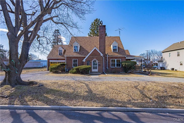 view of front of property with brick siding, a chimney, and a shingled roof