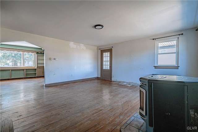 unfurnished living room with hardwood / wood-style flooring, a wood stove, and a healthy amount of sunlight