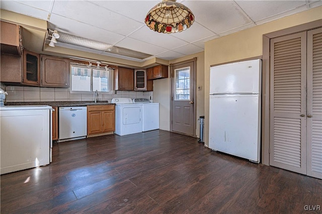 kitchen featuring white appliances, plenty of natural light, dark wood-style flooring, a sink, and washer and clothes dryer