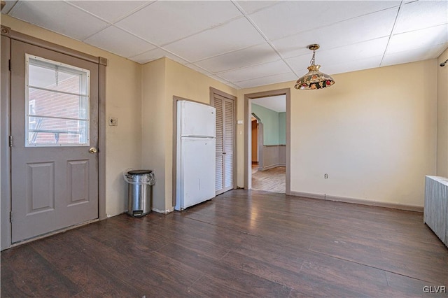 unfurnished room featuring a drop ceiling, baseboards, wood finished floors, and radiator heating unit