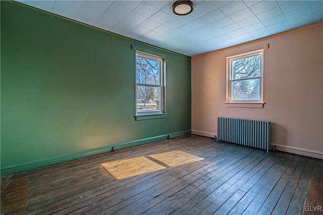 unfurnished room featuring hardwood / wood-style flooring, radiator, baseboards, and ornamental molding