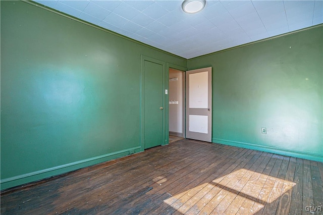 spare room with baseboards and hardwood / wood-style floors