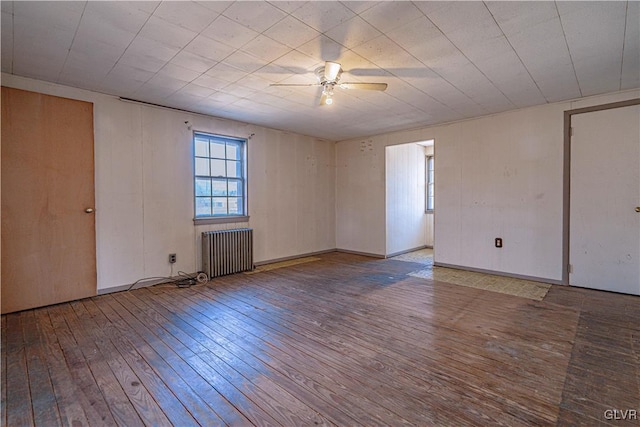 unfurnished room featuring radiator heating unit, a ceiling fan, and hardwood / wood-style flooring