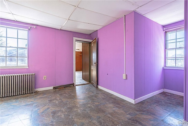 unfurnished room with a drop ceiling, baseboards, and radiator