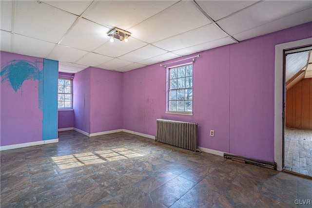 spare room with baseboards, a paneled ceiling, and radiator heating unit