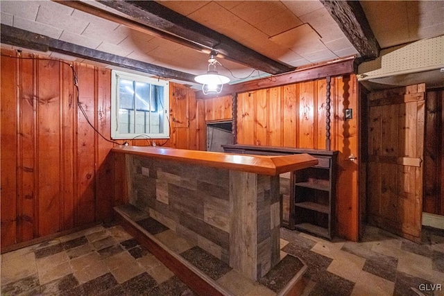 bar featuring beamed ceiling, wood walls, and a bar