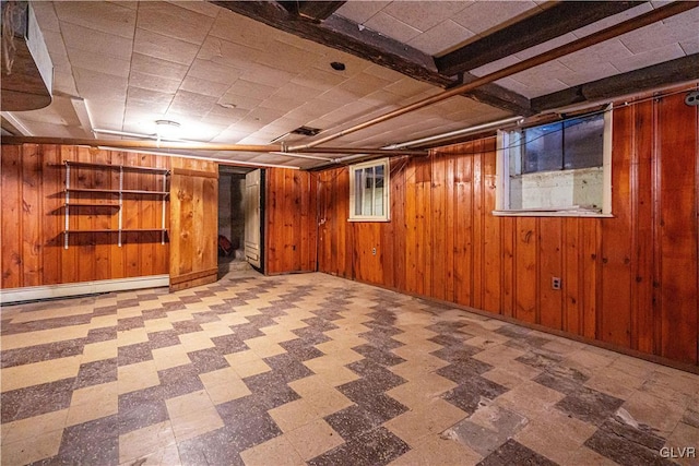 finished below grade area with tile patterned floors, wooden walls, and a baseboard radiator