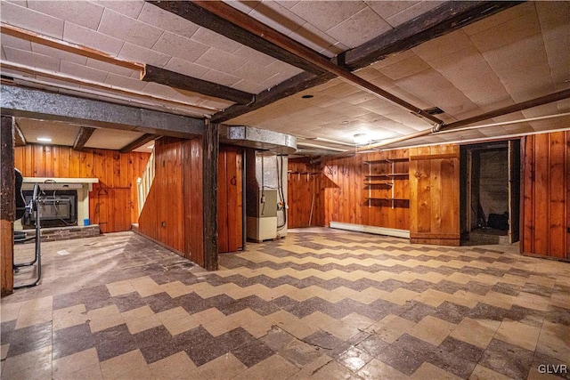 finished below grade area featuring tile patterned floors, a baseboard radiator, and wooden walls