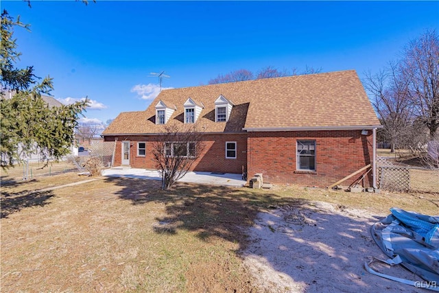 rear view of house with a patio, fence, brick siding, and roof with shingles