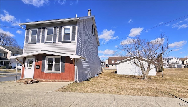 view of side of property featuring entry steps, a yard, and a chimney